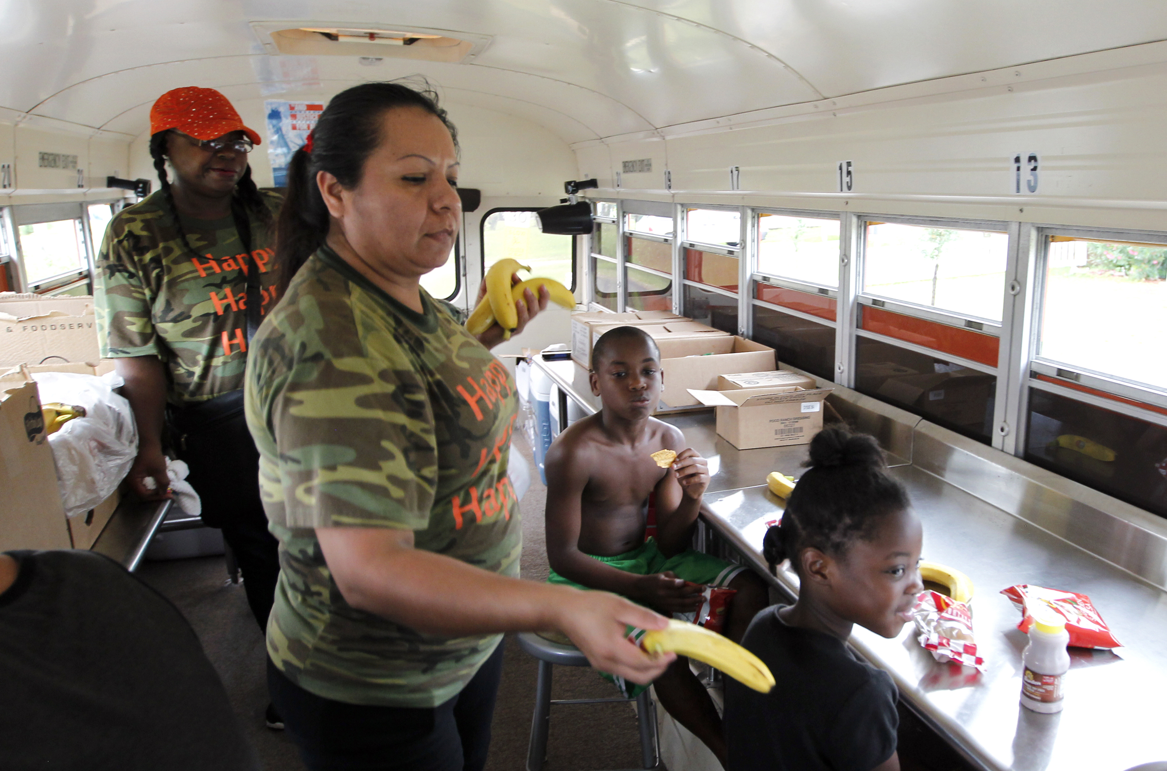 Claudia Fernandez passes out bananas to Texas City school district children during a lunch stop aboard the Nutrition Services' Sting Mobile on Thursday July 17, 2014.   JENNIFER REYNOLDS/The Daily News