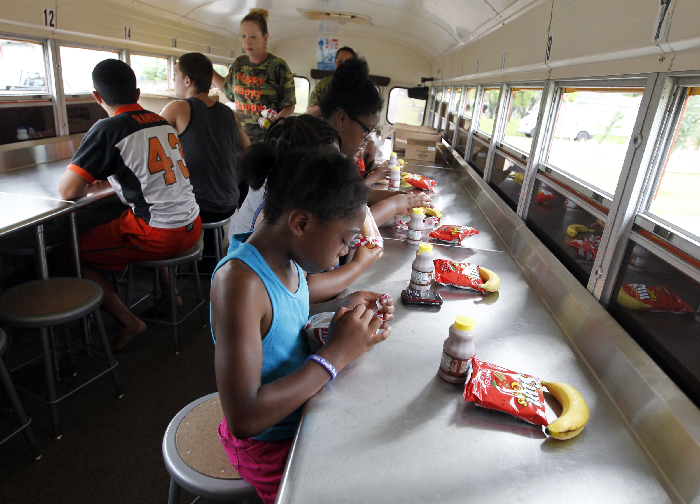 Aiyanna Wyatt, Tia'Kria Walker and Khadijan Wyatt have lunch on Texas City school district Nutrition Services' Sting Mobile during a stop on Thursday July 17, 2014. The school bus, converted to a mobile cafeteria, makes breakfast and lunch stops five days a week. JENNIFER REYNOLDS/The Daily News