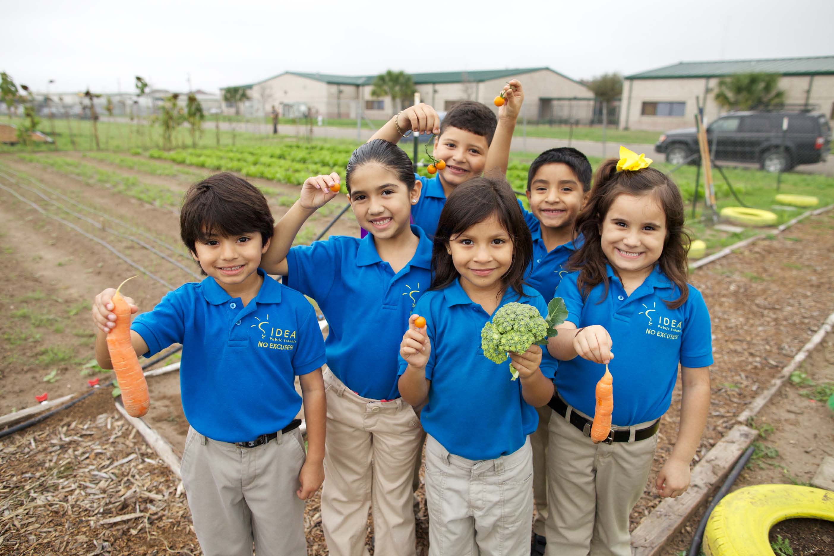 A group of students show off some produce from the farm! Photo by IDEA Public Schools