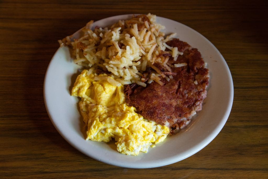 plate with hash browns, corned beef hash, and eggs