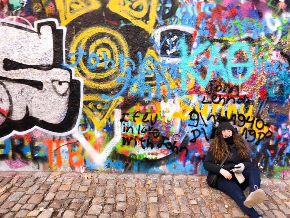 Talia sitting in front of John Lennon Wall in Prague
