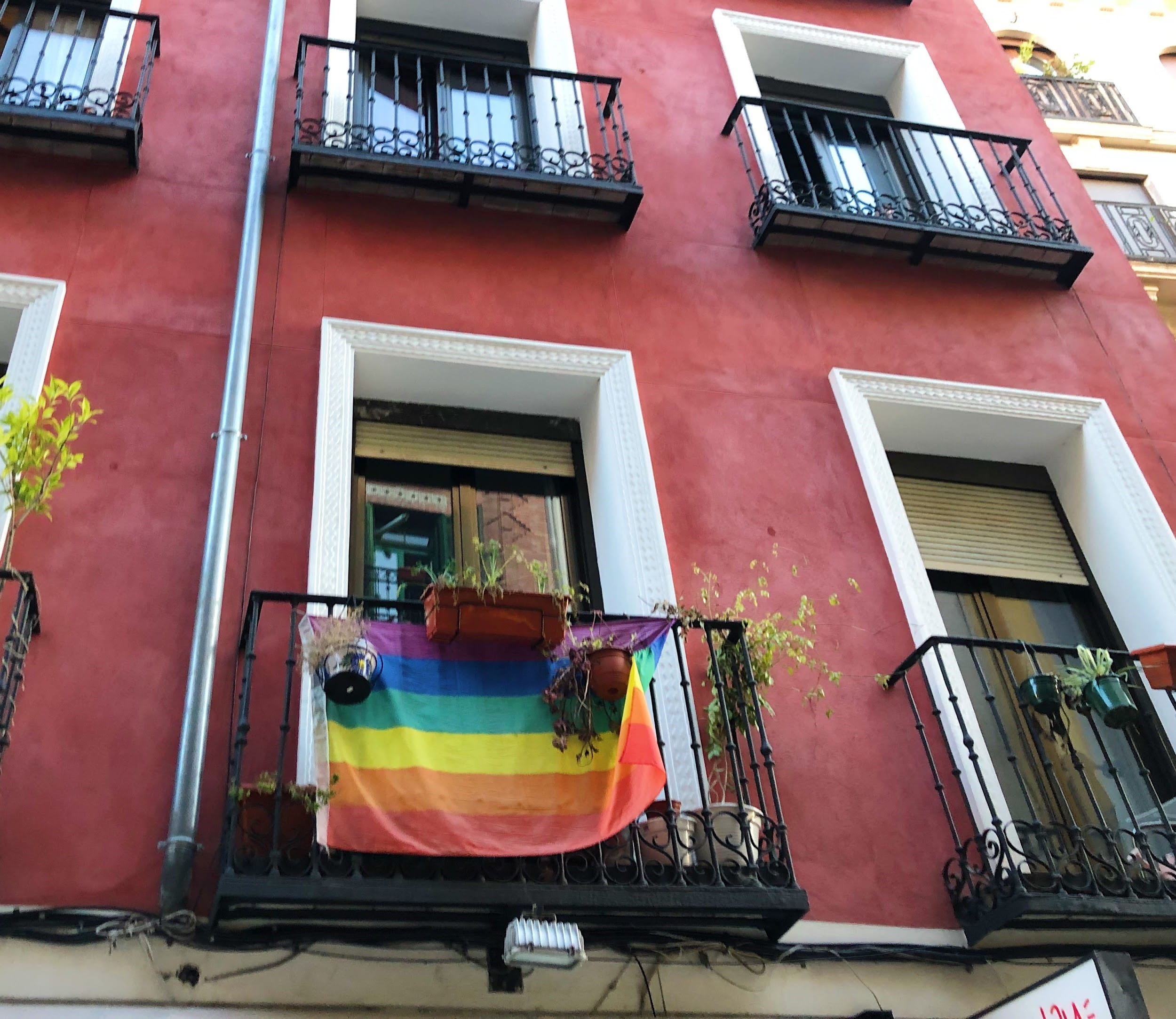 Red building with pride flag hanging from balcony