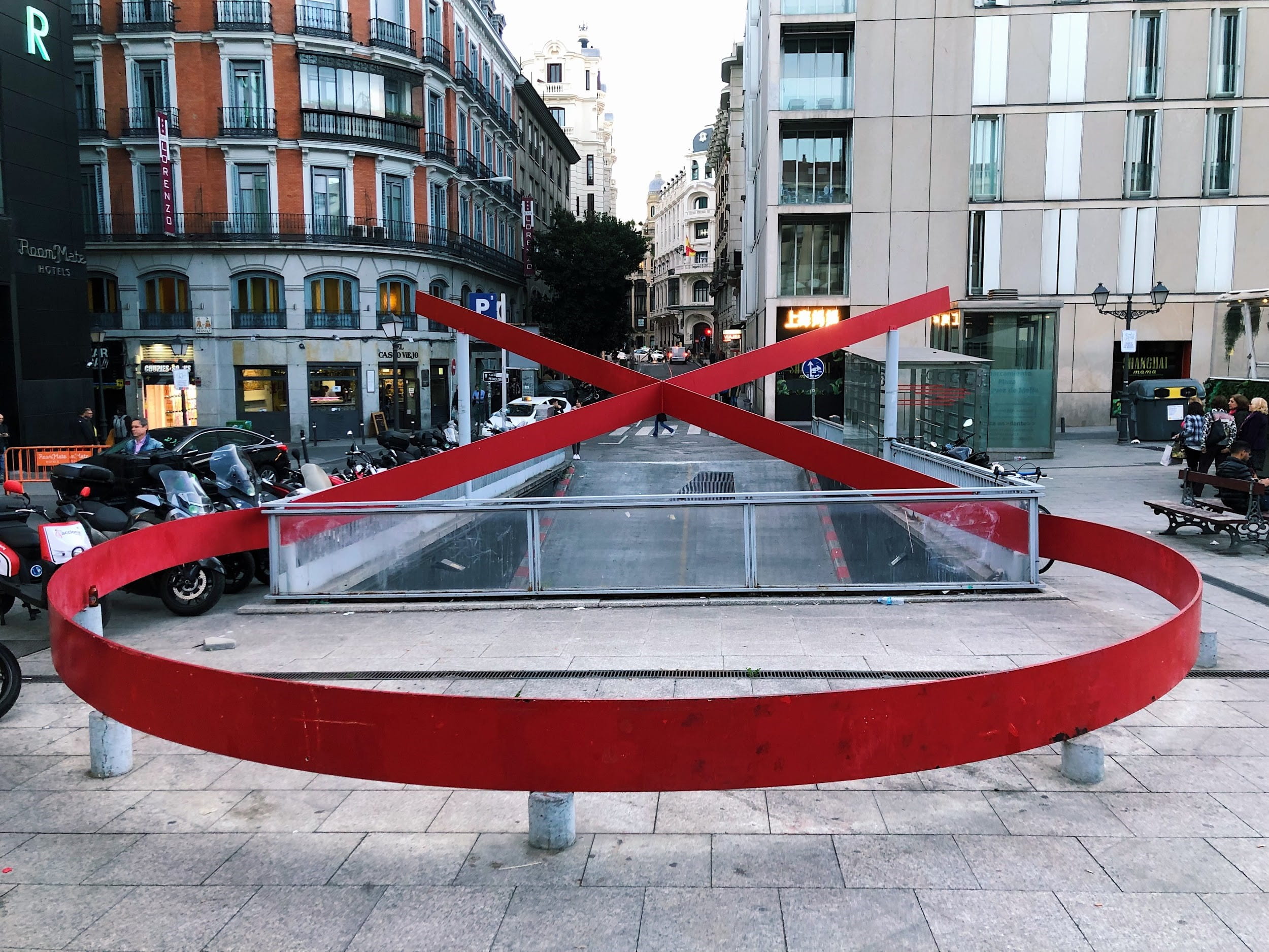large red ribbon monument in front of tall buildings