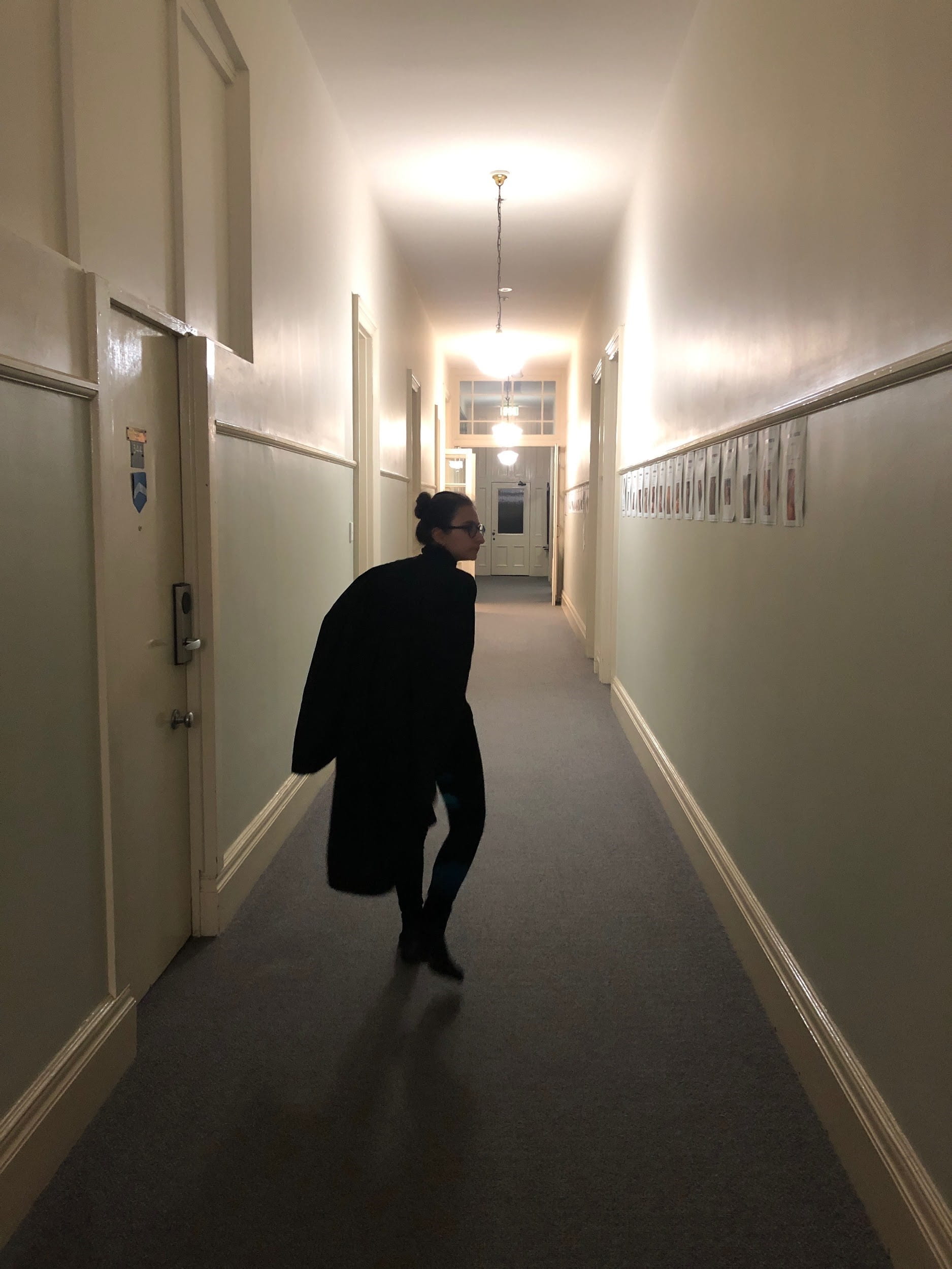 Amanda wearing all black in all white hallway